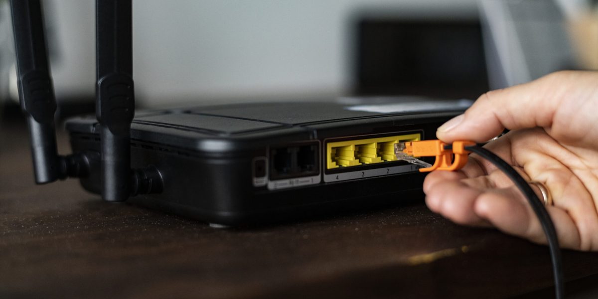 man-plugging-ethernet-cable-wireless-router-scaled.jpg - PresaObiectiva